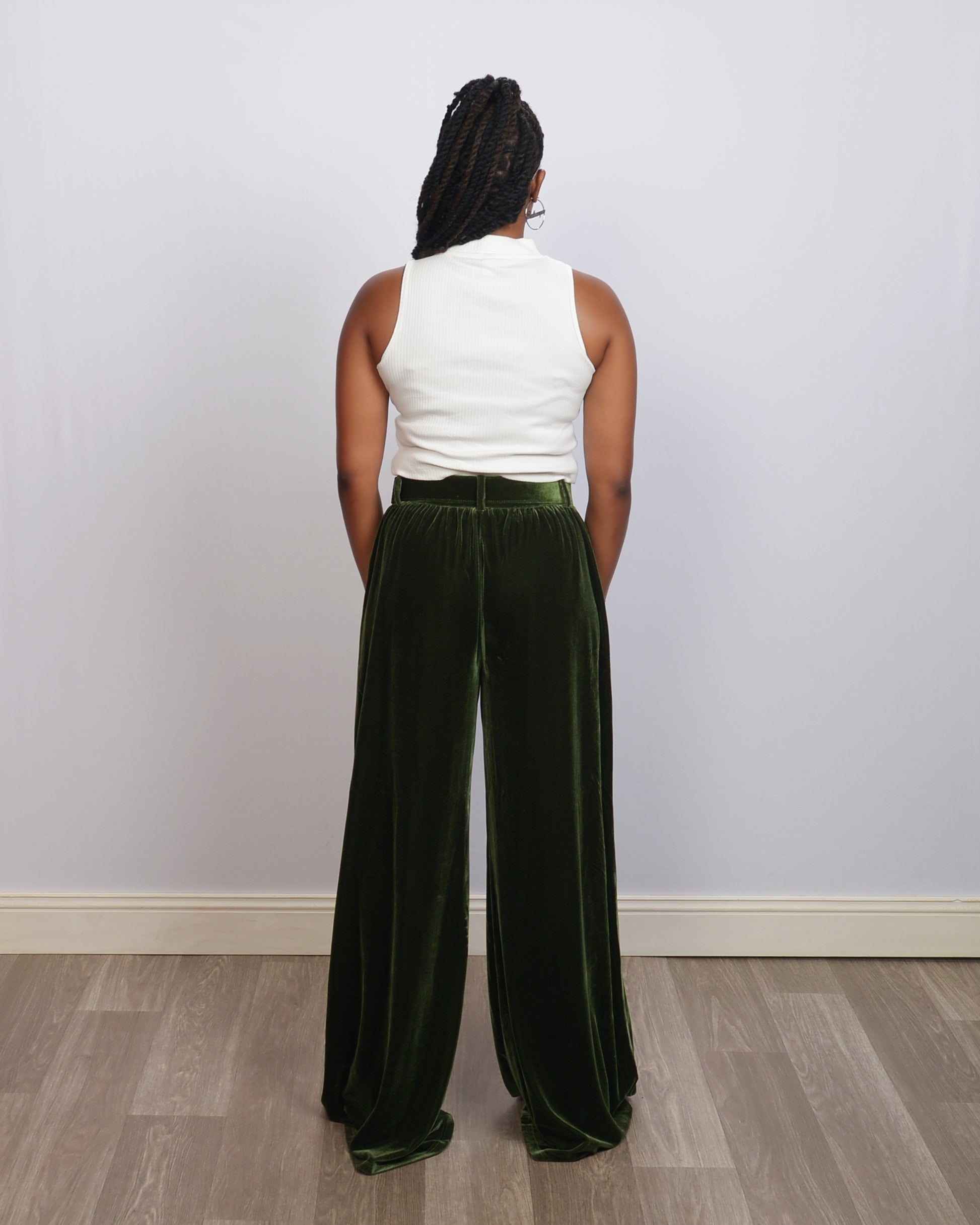 Rear view of green velvet pants with wide-leg silhouette and matching belt, worn by a tall woman