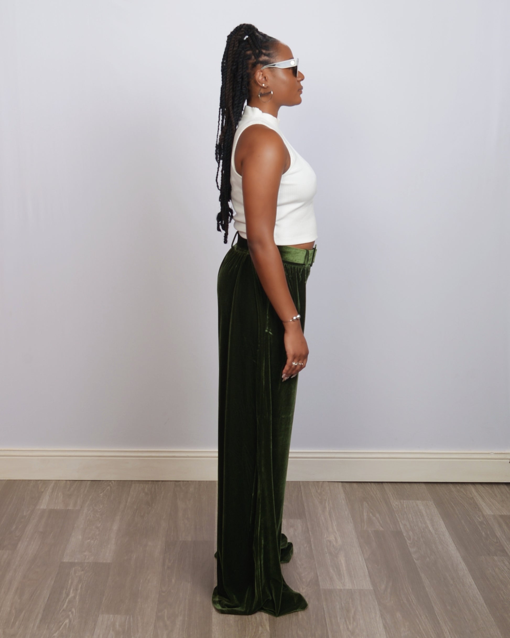 Side profile of a tall woman in emerald velvet wide-leg pants, showing the dramatic length and high waist fit.